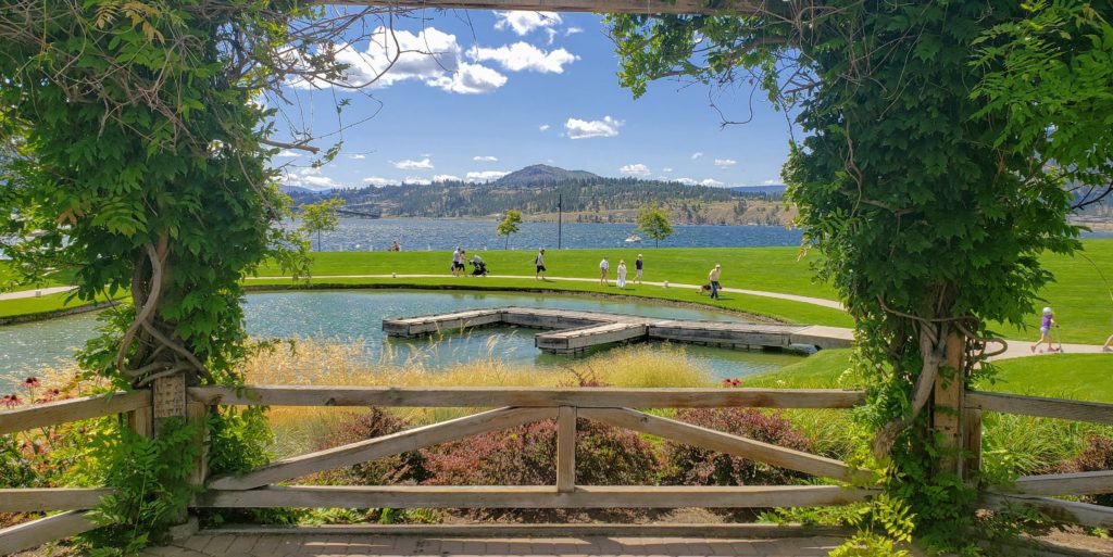 A view of a dock on a lagoon with a grassy berm and a lake in the distance