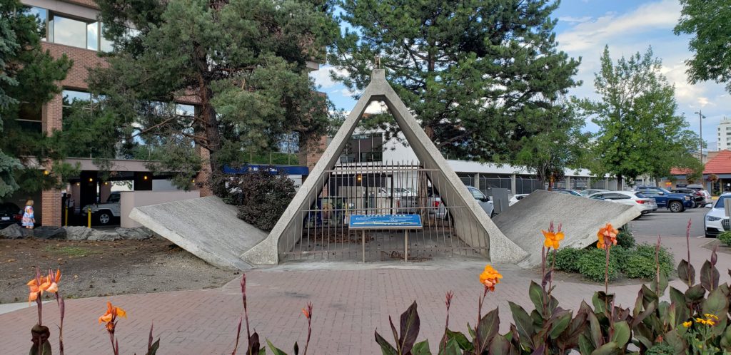 A plaza lined with planted beds contains an enormous concrete anchor. The inside of the anchor is 